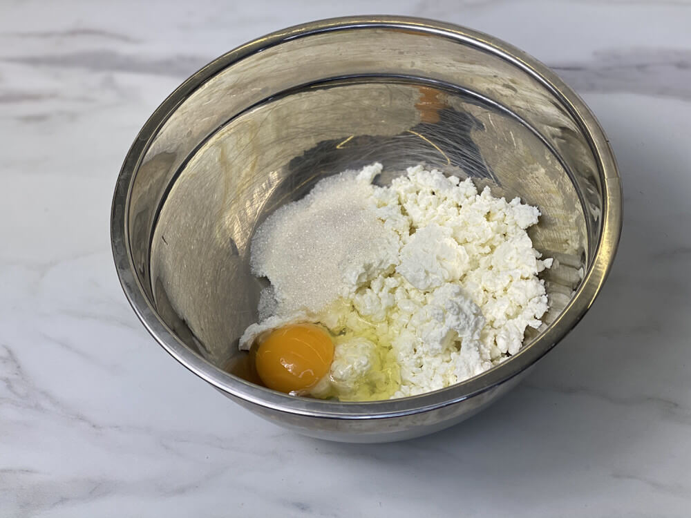 Добавьте в творог яйцо, соль и сахар